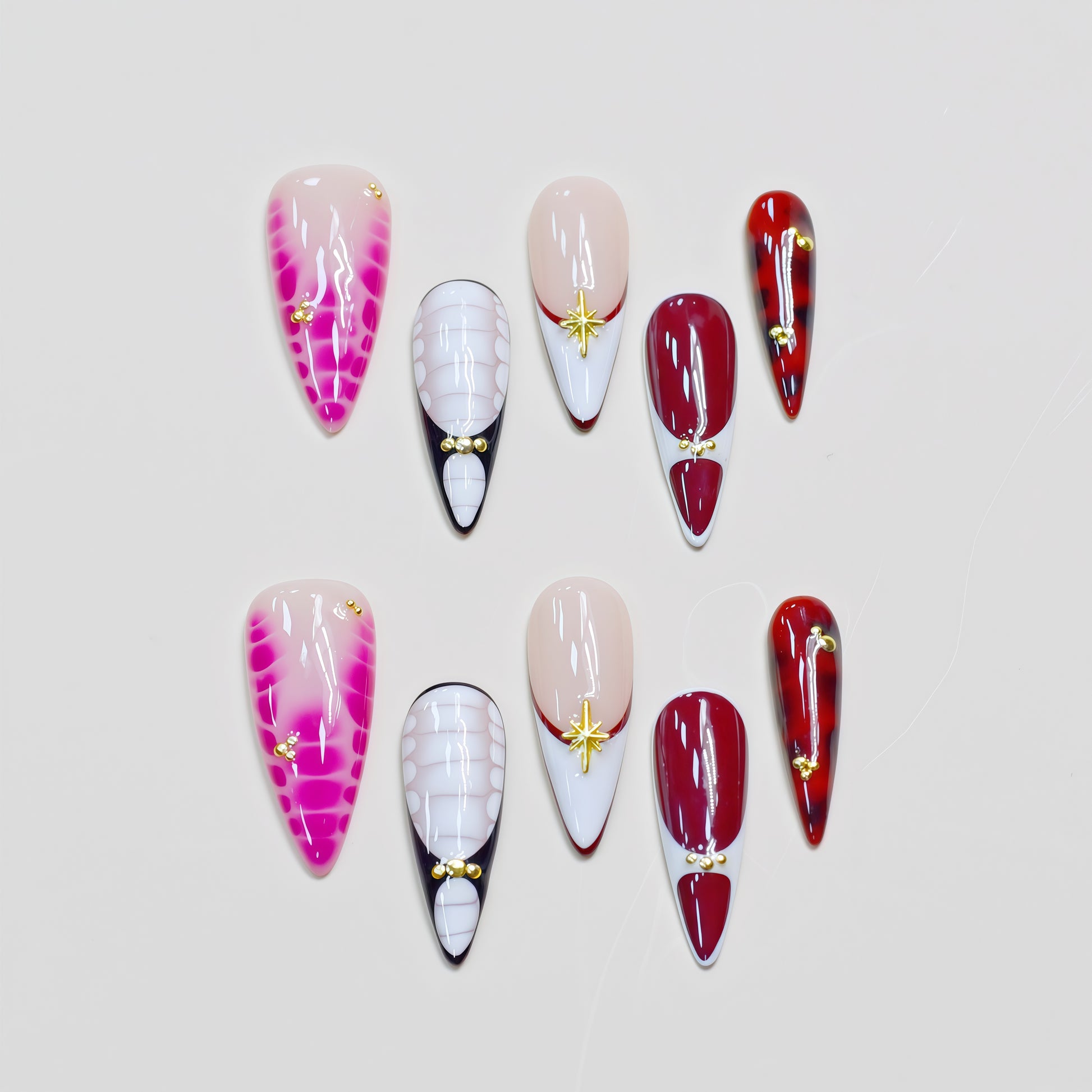 Hands wearing Crimson Elegance stiletto press-on nails in deep red and white with gold accents, styled with rings for a luxurious look.