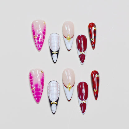 Hands wearing Crimson Elegance stiletto press-on nails in deep red and white with gold accents, styled with rings for a luxurious look.