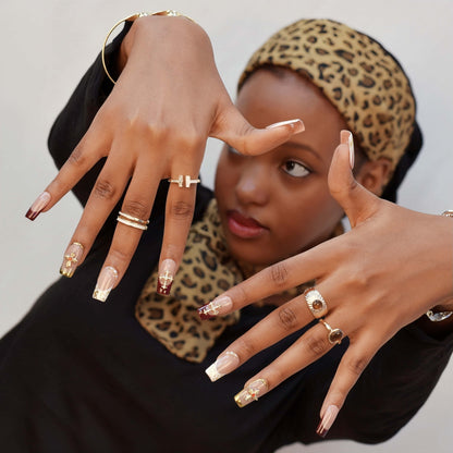 Crimson Grace press-on nails featuring red and nude tones, gold crosses, pearls, and metallic gold frames for a luxurious festive look.