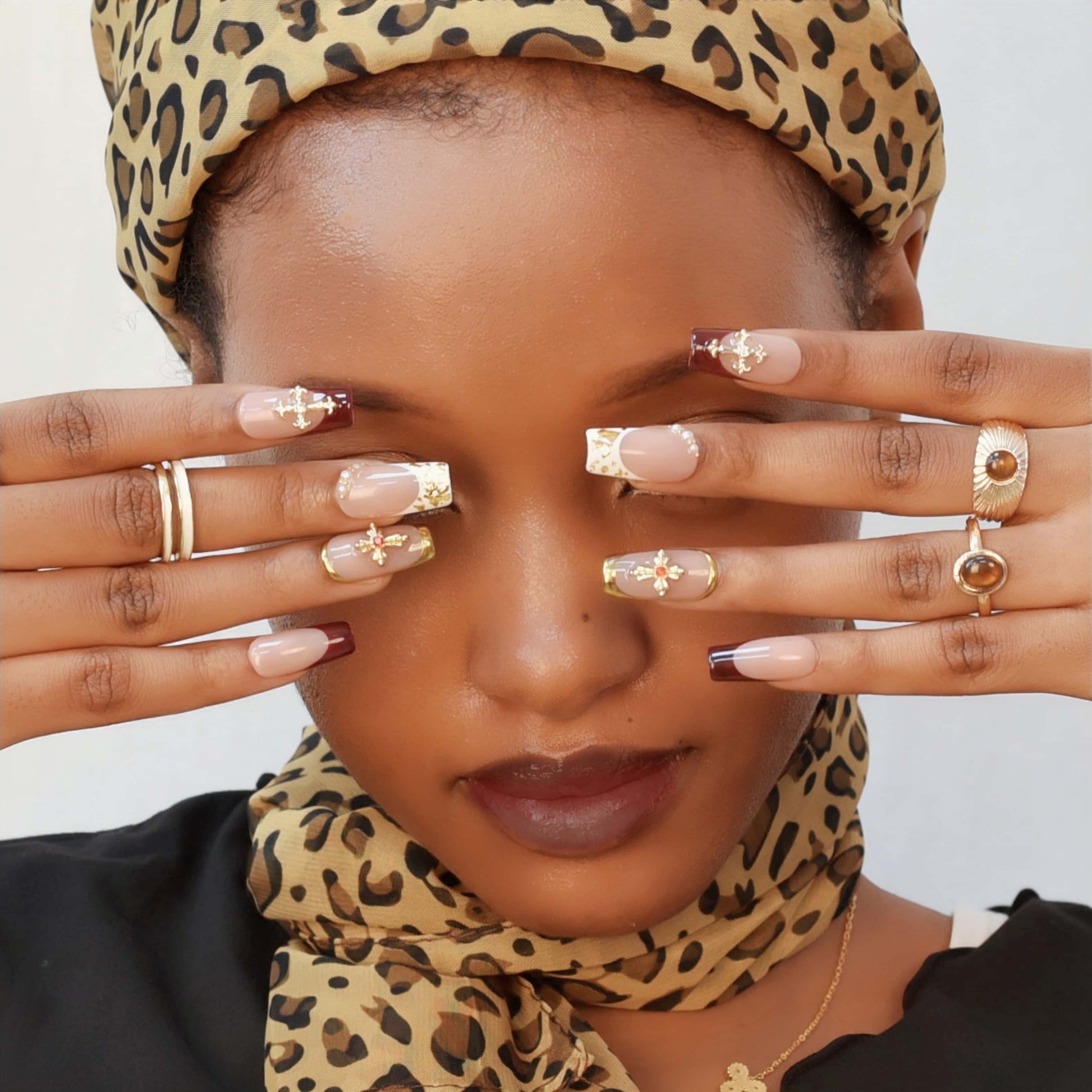 Crimson Grace press-on nails featuring red and nude tones, gold crosses, pearls, and metallic gold frames for a luxurious festive look.