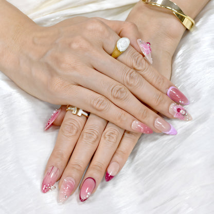 Medium Almond press-on nails in crimson and pink ombré with 3D orchid flowers, hand-painted streaks, and rhinestone accents.