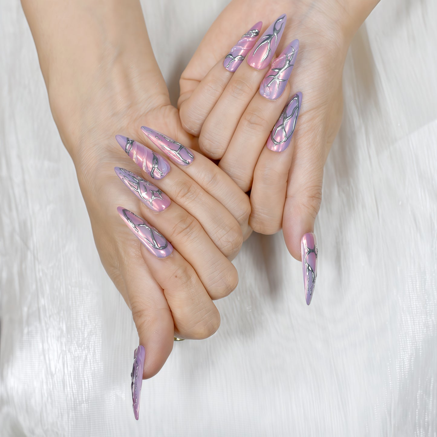 Cyber Crush press-on nails by You Are Angel with pink-purple chrome base and sculpted silver metallic designs in long stiletto shape.