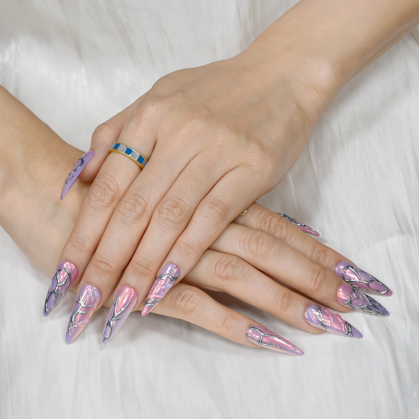 Cyber Crush press-on nails by You Are Angel with pink-purple chrome base and sculpted silver metallic designs in long stiletto shape.