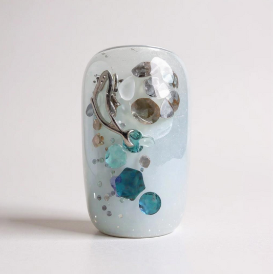 Handmade press-on nails with silver glitter base, blue gemstone accents, and celestial-inspired detailing in a cosmic theme