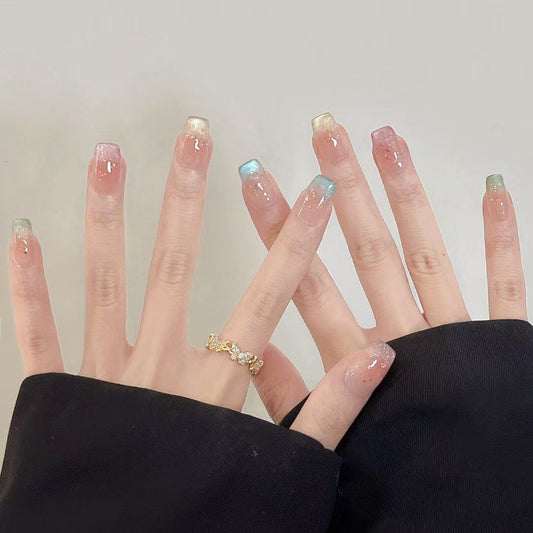 Hand wearing Éclat Nailery’s Champagne Cloud press-on nails – nude base with champagne glitter ombré, square shape, elegant and minimalist design.