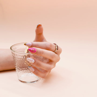 Hand with painted nails holding a clear glass against a beige background