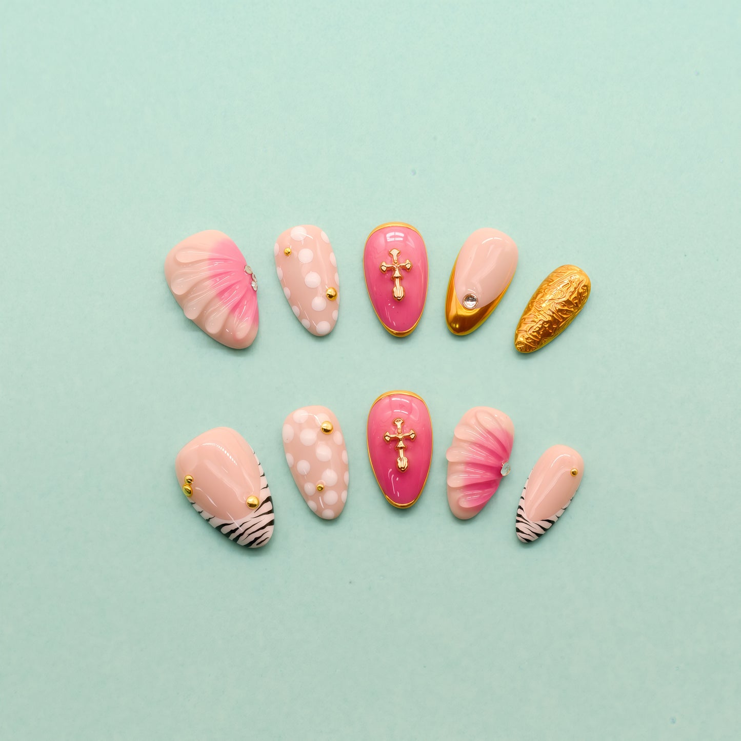 Almond press-on nails with zebra stripes, pink 3D shells, polka dots, gold cross embellishments, and chrome gold tip – Electric Pop Royale set.