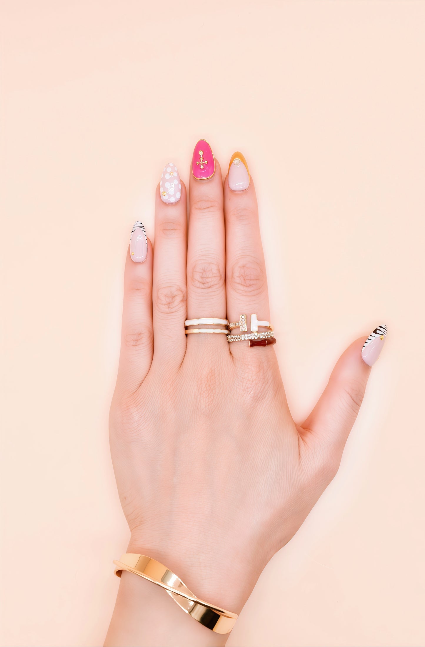 Almond press-on nails with zebra stripes, pink 3D shells, polka dots, gold cross embellishments, and chrome gold tip – Electric Pop Royale set on hand