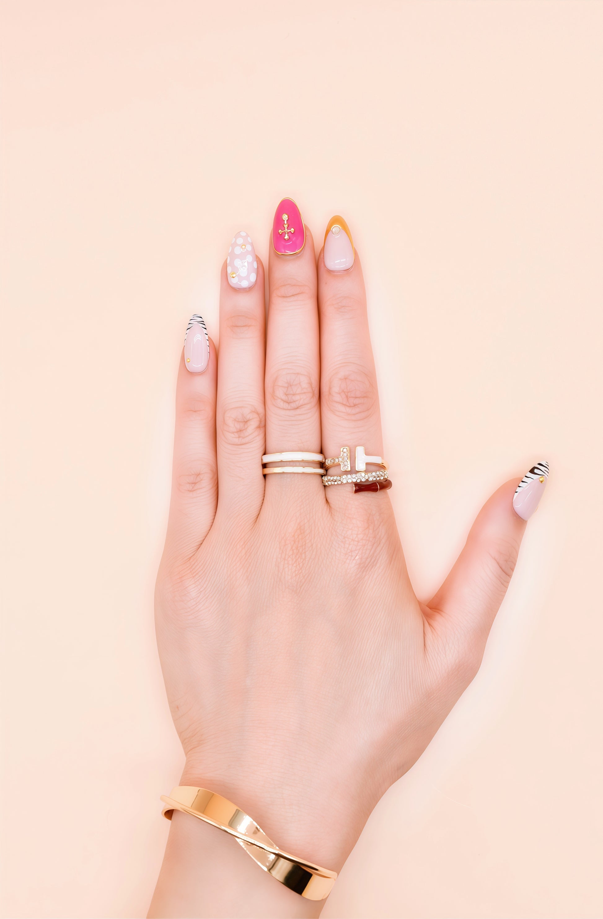 Almond press-on nails with zebra stripes, pink 3D shells, polka dots, gold cross embellishments, and chrome gold tip – Electric Pop Royale set on hand