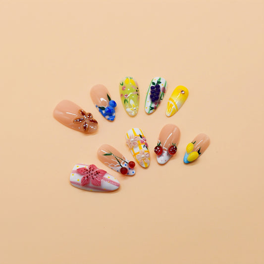 Medium Almond press-on nails featuring cherries, lemons, grapes, and floral embellishments in a colorful fruity design – Fruit Garden Bloom nail set.