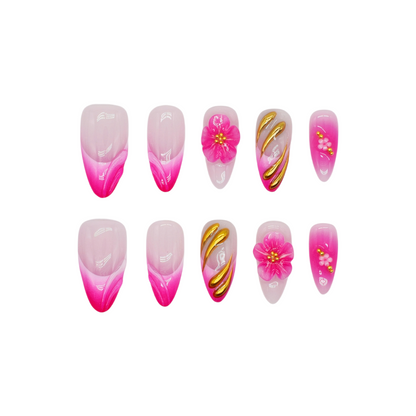 Medium almond press-on nails in pink ombré with 3D pink flowers, gold sculpting, and floral accents.
