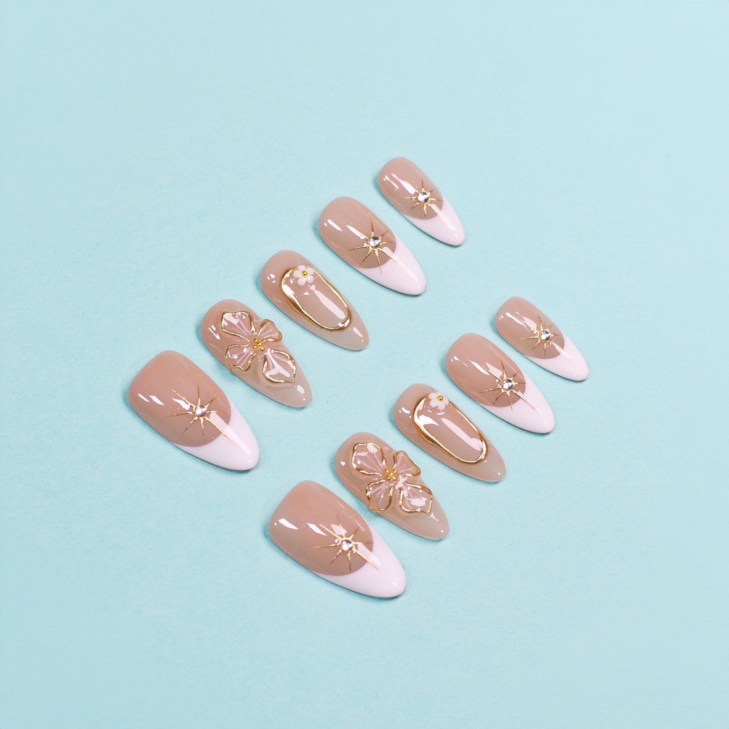 Medium almond press-on nails in nude and white French tips with 3D gold flowers, gemstone accents, and gold frames.
