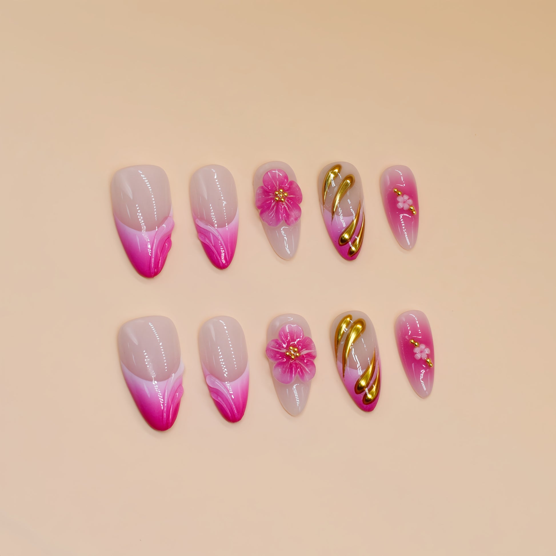 Medium almond press-on nails in pink ombré with 3D pink flowers, gold sculpting, and floral accents.