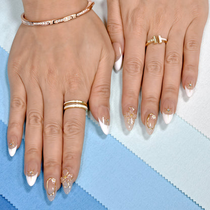 Medium almond press-on nails in nude and white French tips with 3D gold flowers, gemstone accents, and gold frames.