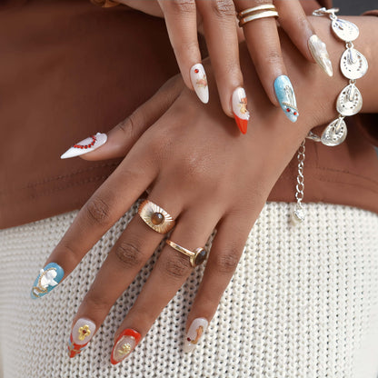 Heavenly Heartstrings press-on nails featuring angel and heart motifs, pearls, gold accents, and red French tips with celestial designs.