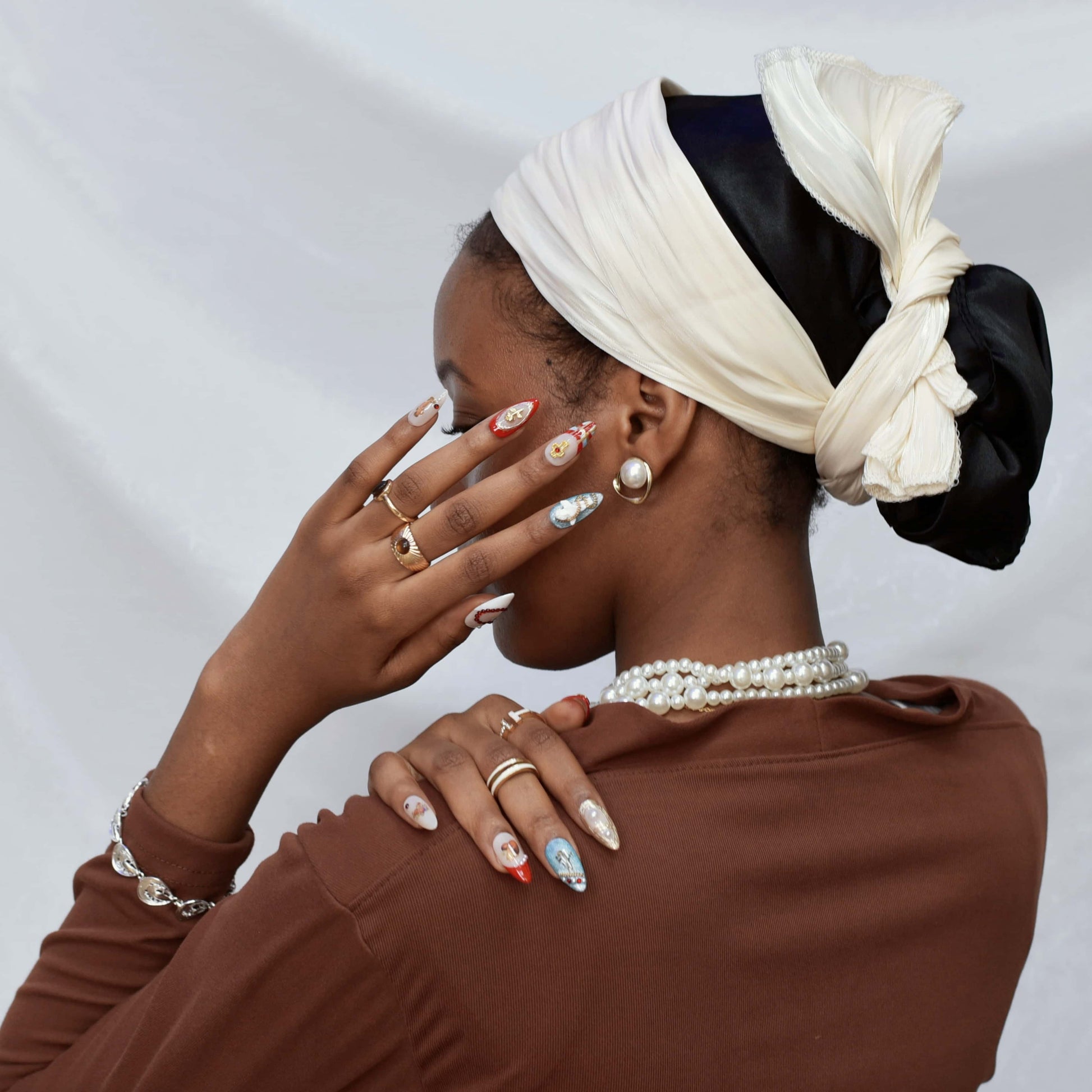 Heavenly Heartstrings press-on nails featuring angel and heart motifs, pearls, gold accents, and red French tips with celestial designs.