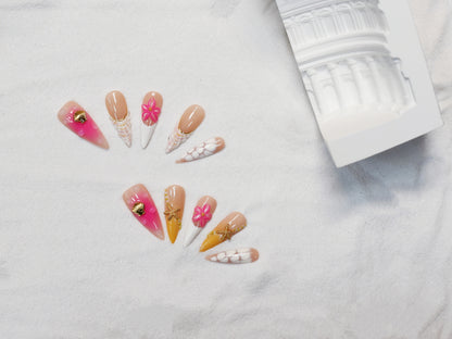 Long stiletto tropical press-on nails featuring vibrant pink and orange gradients, 3D starfish and gold seashell accents – Island Glow nail set.