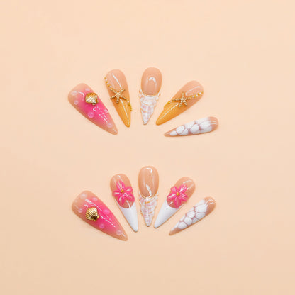 Long stiletto tropical press-on nails featuring vibrant pink and orange gradients, 3D starfish and gold seashell accents – Island Glow nail set.