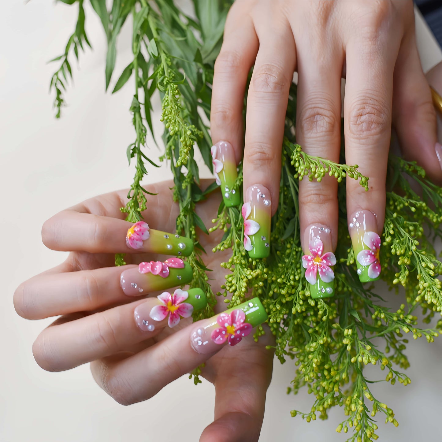 Handmade lime green floral press-on nails with 3D pink flowers and rhinestone accents on long square glossy nails