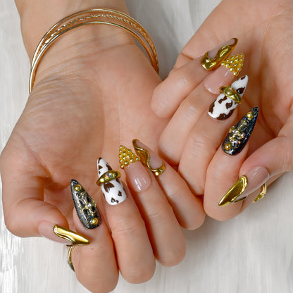 Midnight Rodeo press-on nails featuring gold metal accents, black glitter, cow print, and nude tones for a bold Western-glam look.