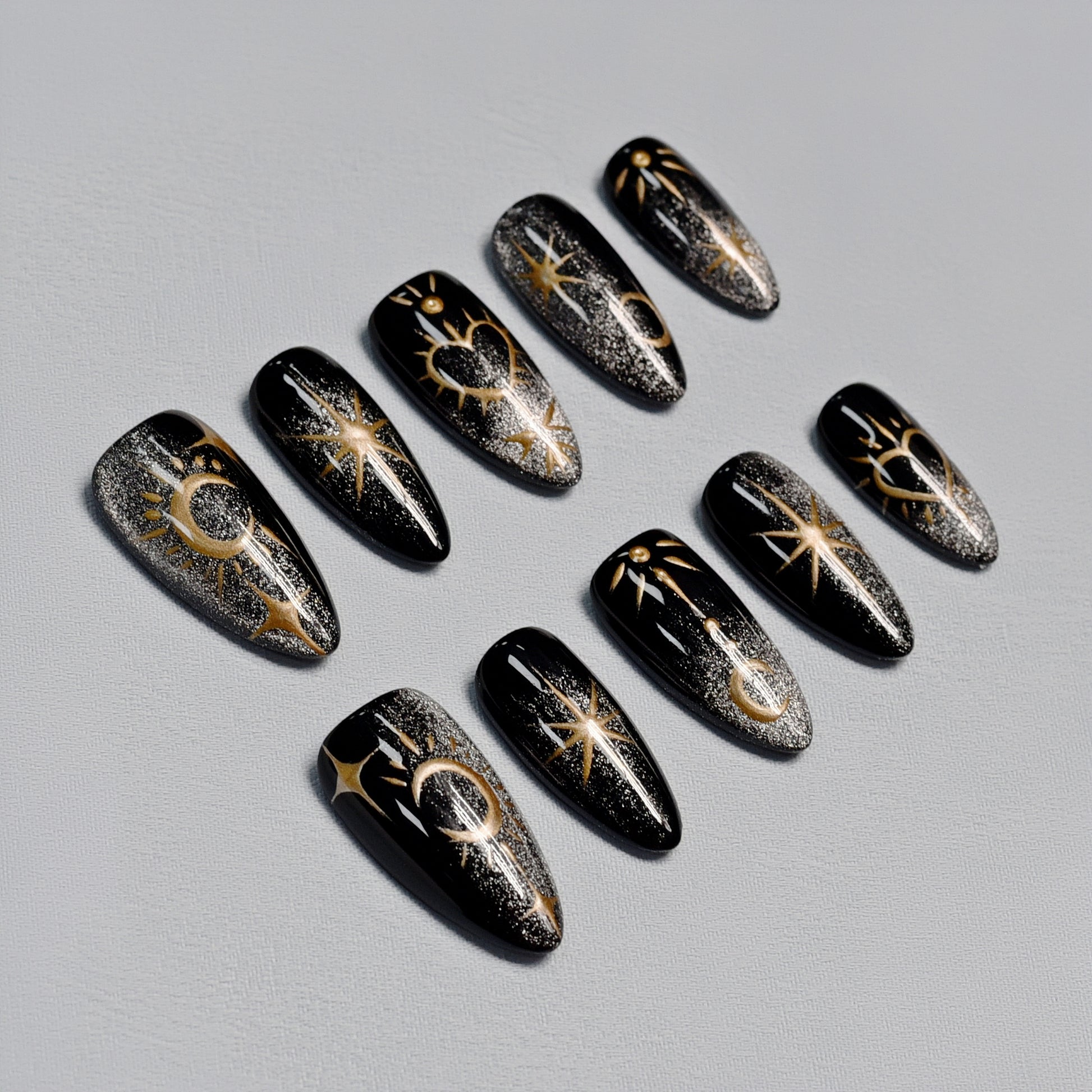 Moonlight Ritual handmade press-on nails by You Are Angel featuring black base with gold celestial art including moons, stars, and hearts.