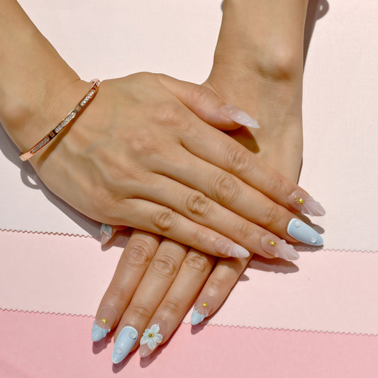 Pastel blue and pink press on nails with 3D floral accents, gold beads, and almond shape – Tropical Bloom Collection.