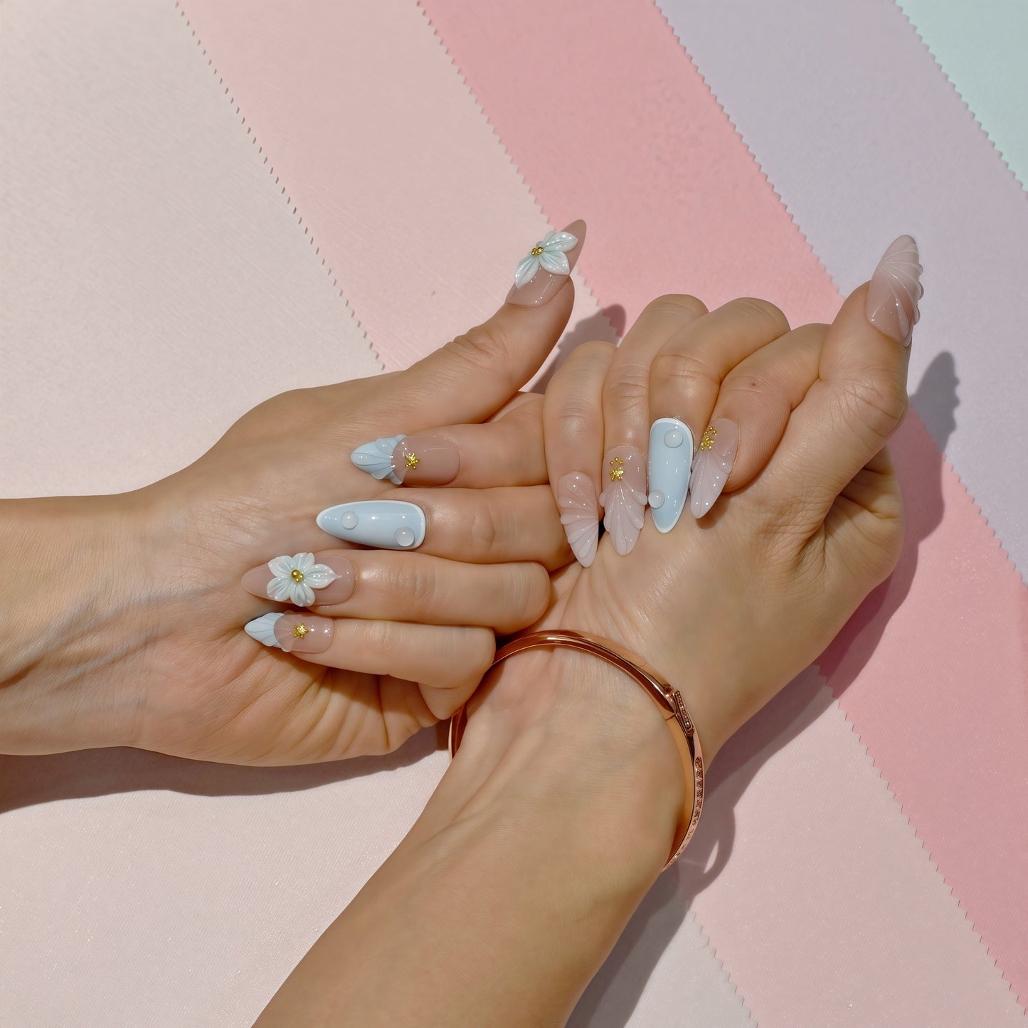 Pastel blue and pink press on nails with 3D floral accents, gold beads, and almond shape – Tropical Bloom Collection.