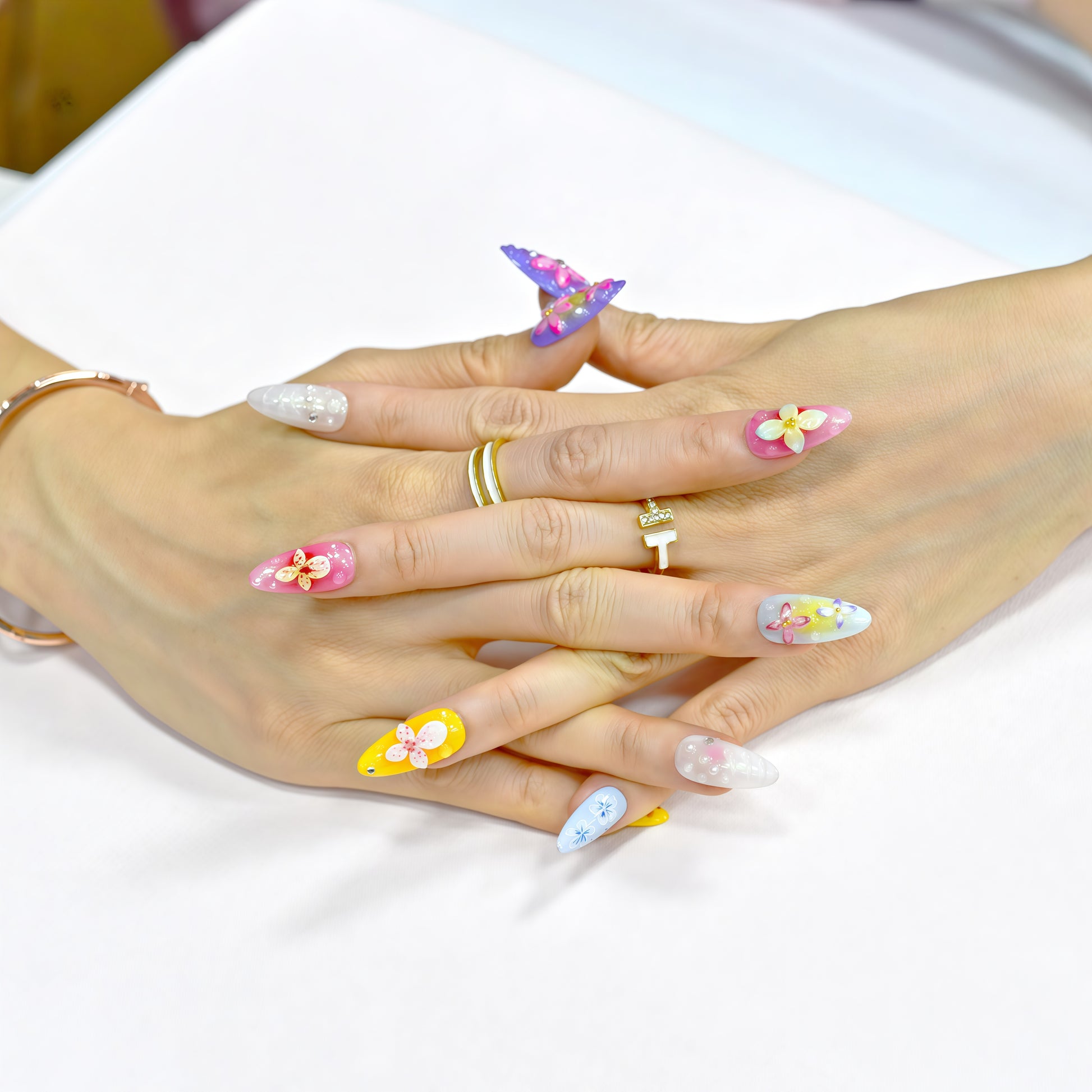 Medium almond press-on nails with bright floral 3D designs in purple, pink, yellow, and white – Petal Parade handmade nail set.