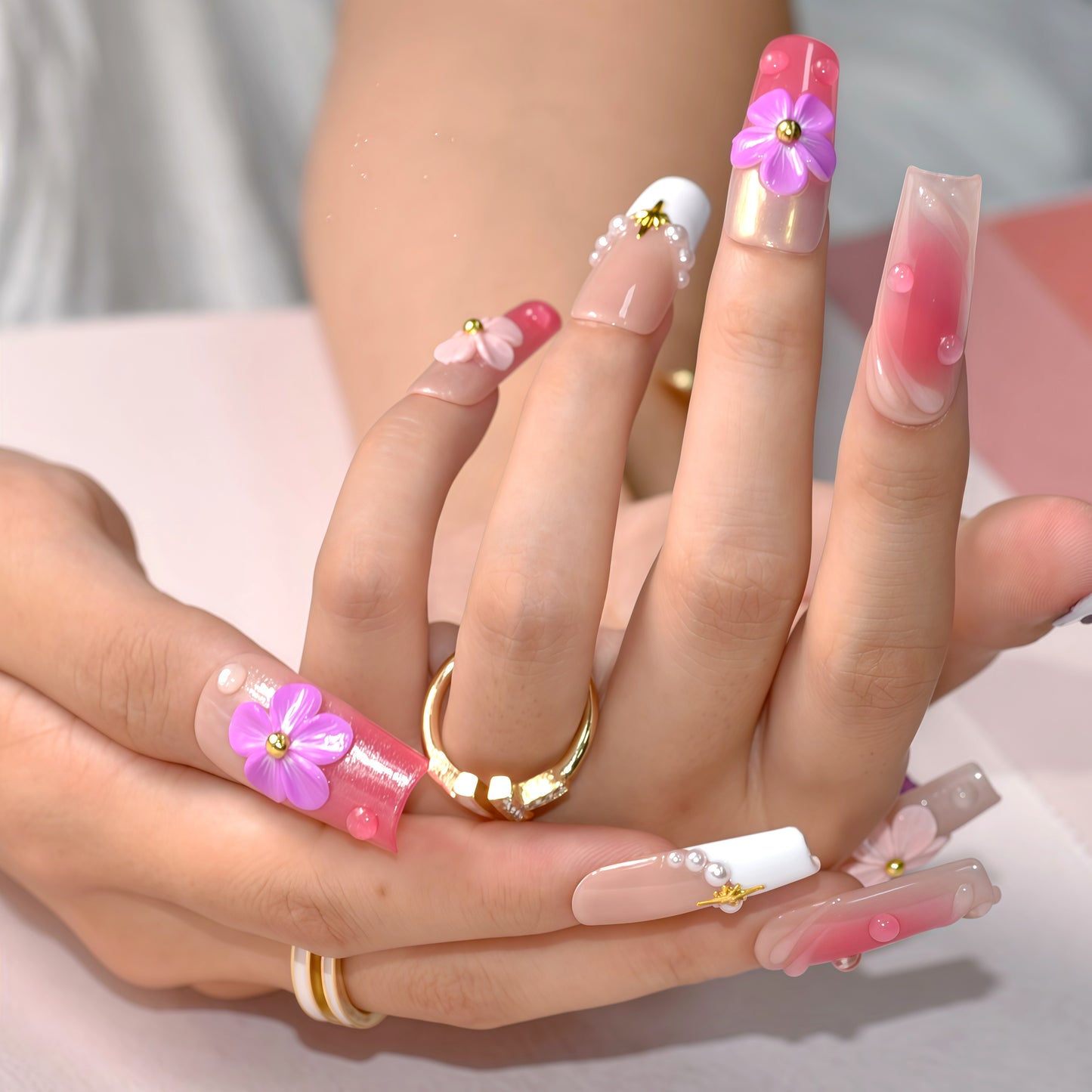 Close-up of a hand with pink and white floral nail art on a neutral background
