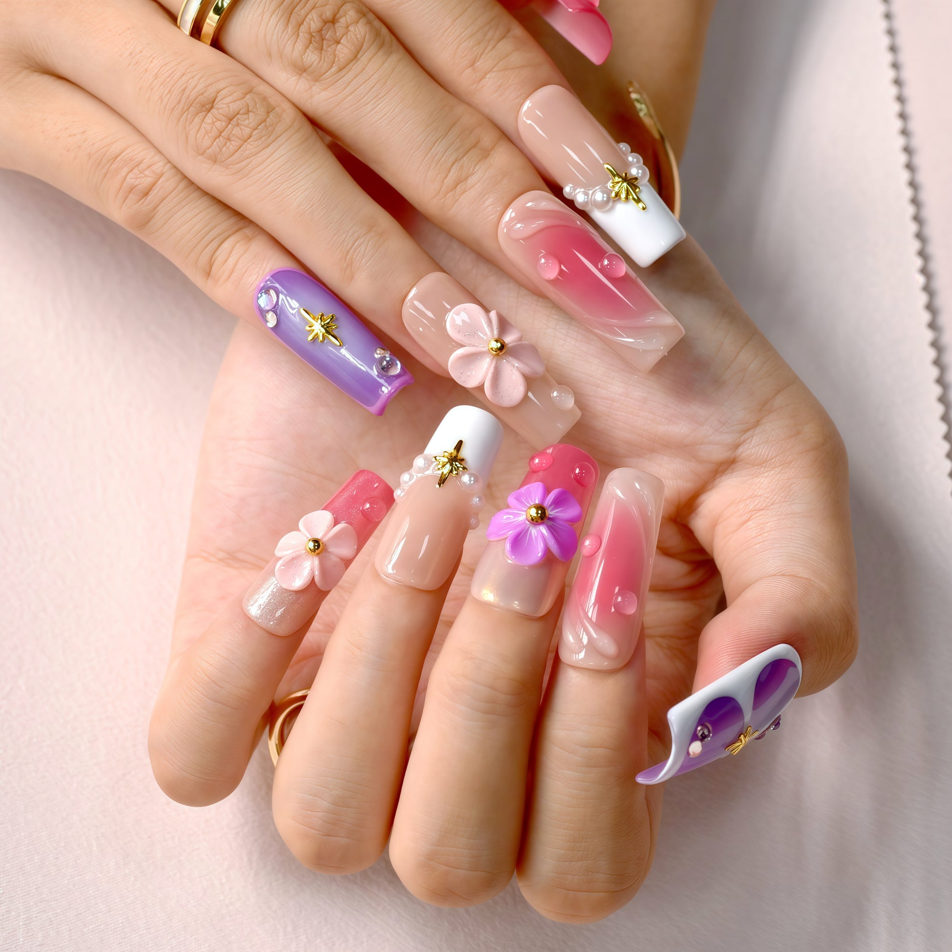 Close-up of hands with colorful floral nail designs on a light pink background