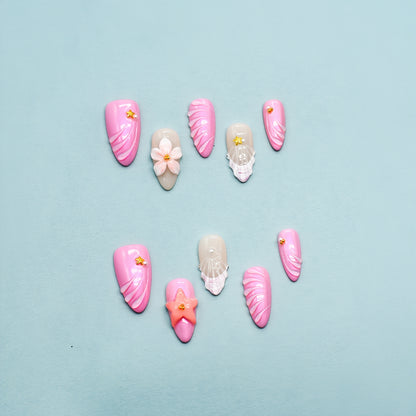 Medium Almond pink shimmer press-on nails with 3D flowers, gem embellishments, and draped texture design.