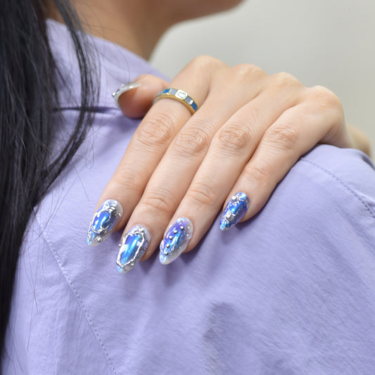 Almond-shaped press-on nails in holographic blue with silver chrome lines and 3D metallic accents – Blue Steel Siren set.