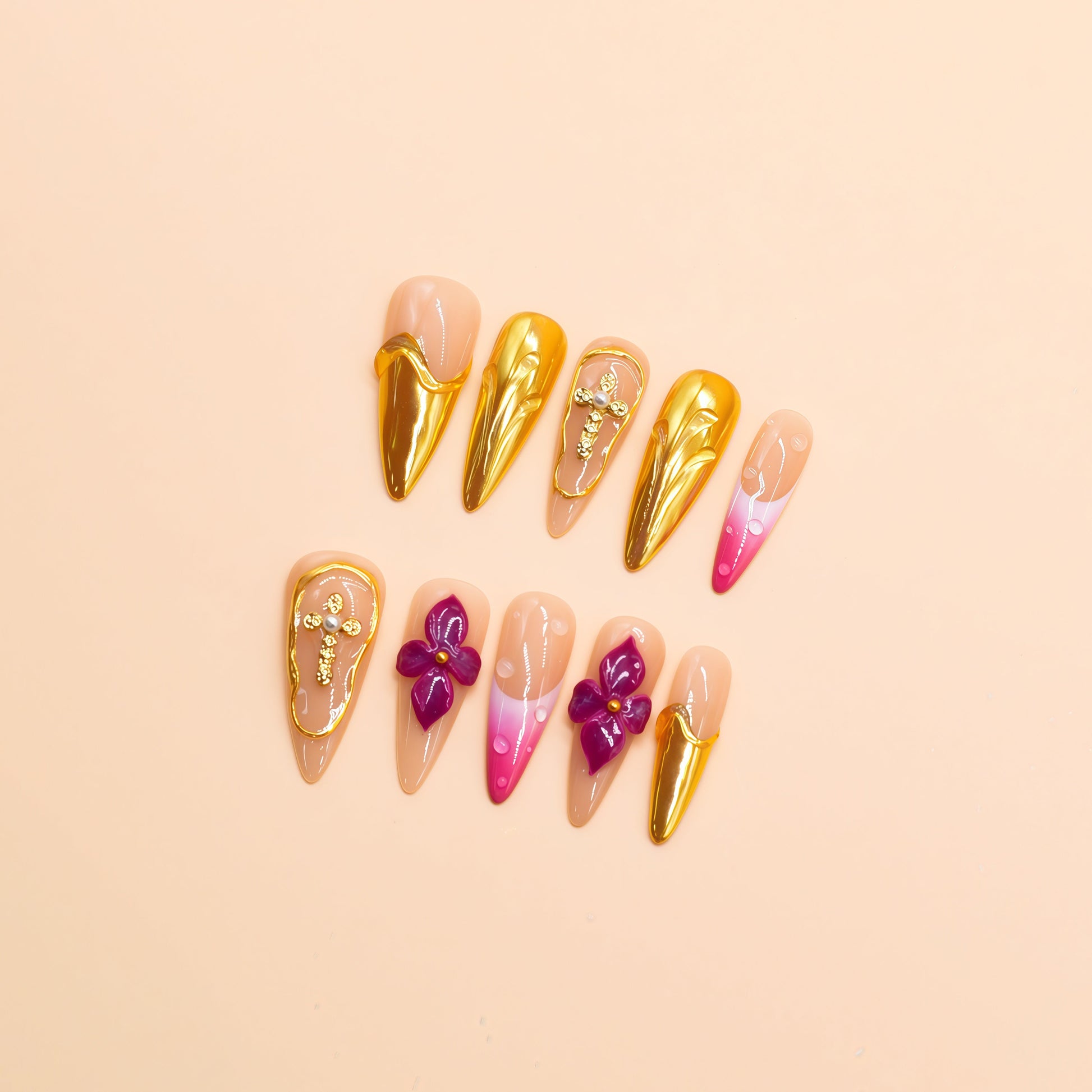 Royal Bloom press-on nails by You Are Angel with gold chrome accents, pink floral art, jeweled crosses, and long stiletto shape.