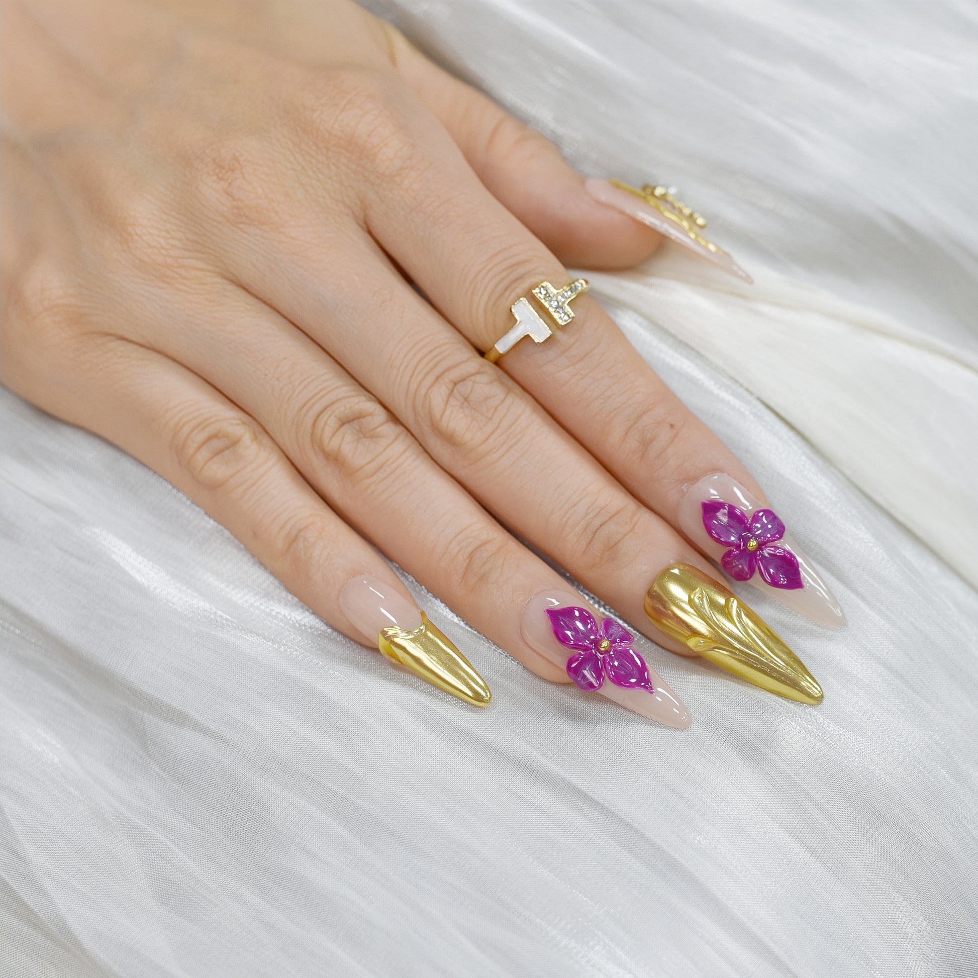 Royal Bloom press-on nails by You Are Angel with gold chrome accents, pink floral art, jeweled crosses, and long stiletto shape.