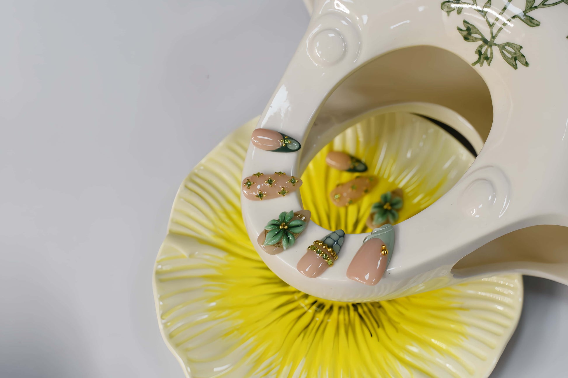 Sage green floral press on nails with gold embellishments and delicate botanical artwork.
