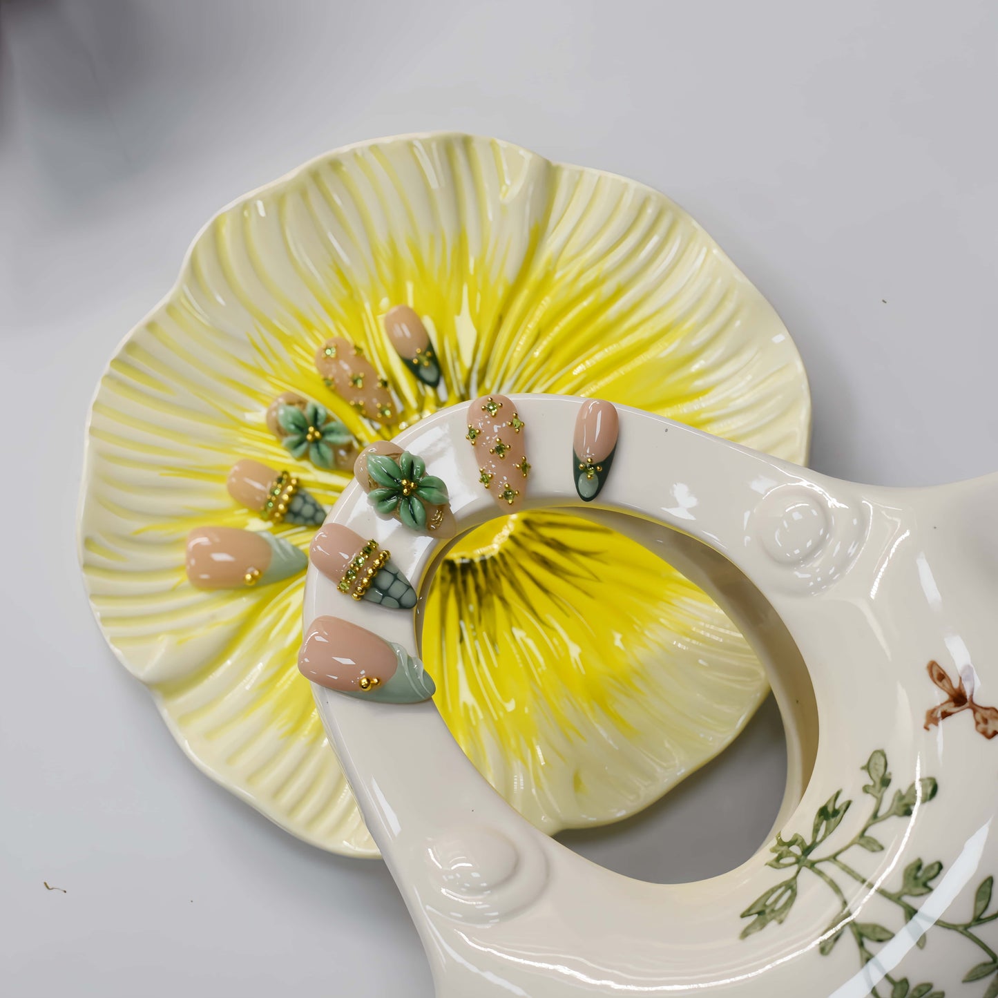 Sage green floral press on nails with gold embellishments and delicate botanical artwork.
