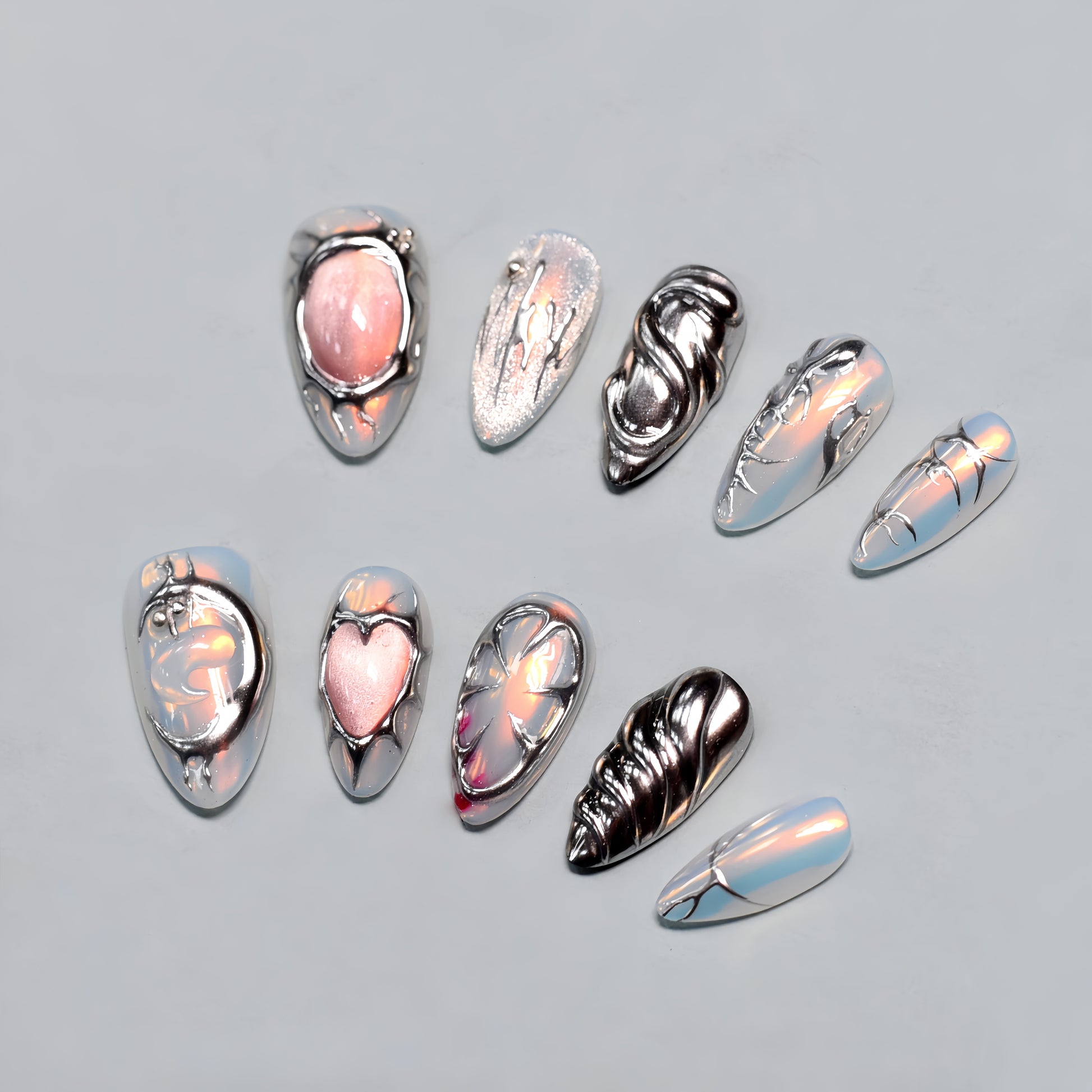 Medium Almond press-on nails with chrome textures, sculptural 3D hearts and swirls, and pearlescent nude base — Silver Luster Muse.