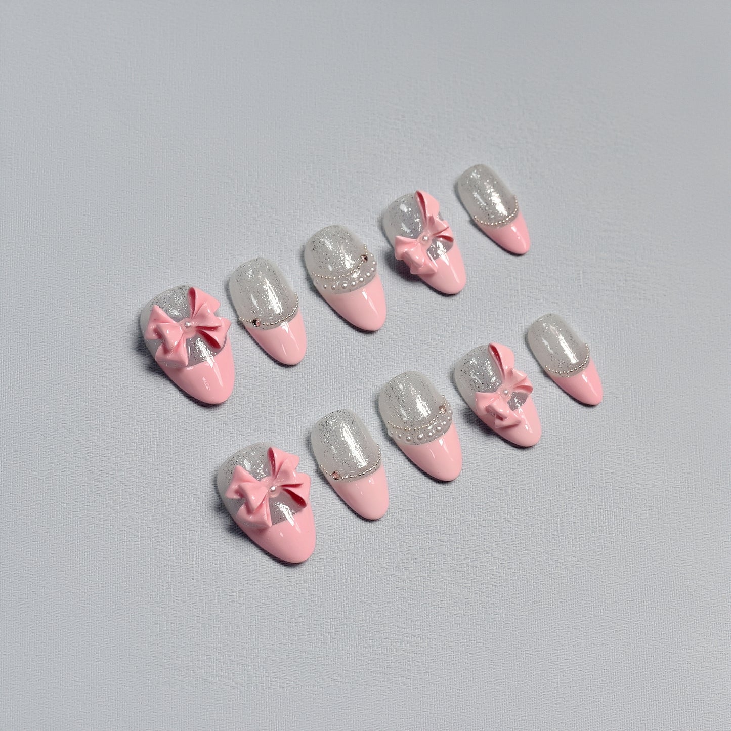 Sugar Bow handmade press-on nails by You Are Angel with pink base, silver glitter, and 3D pink bows for a soft and feminine look.