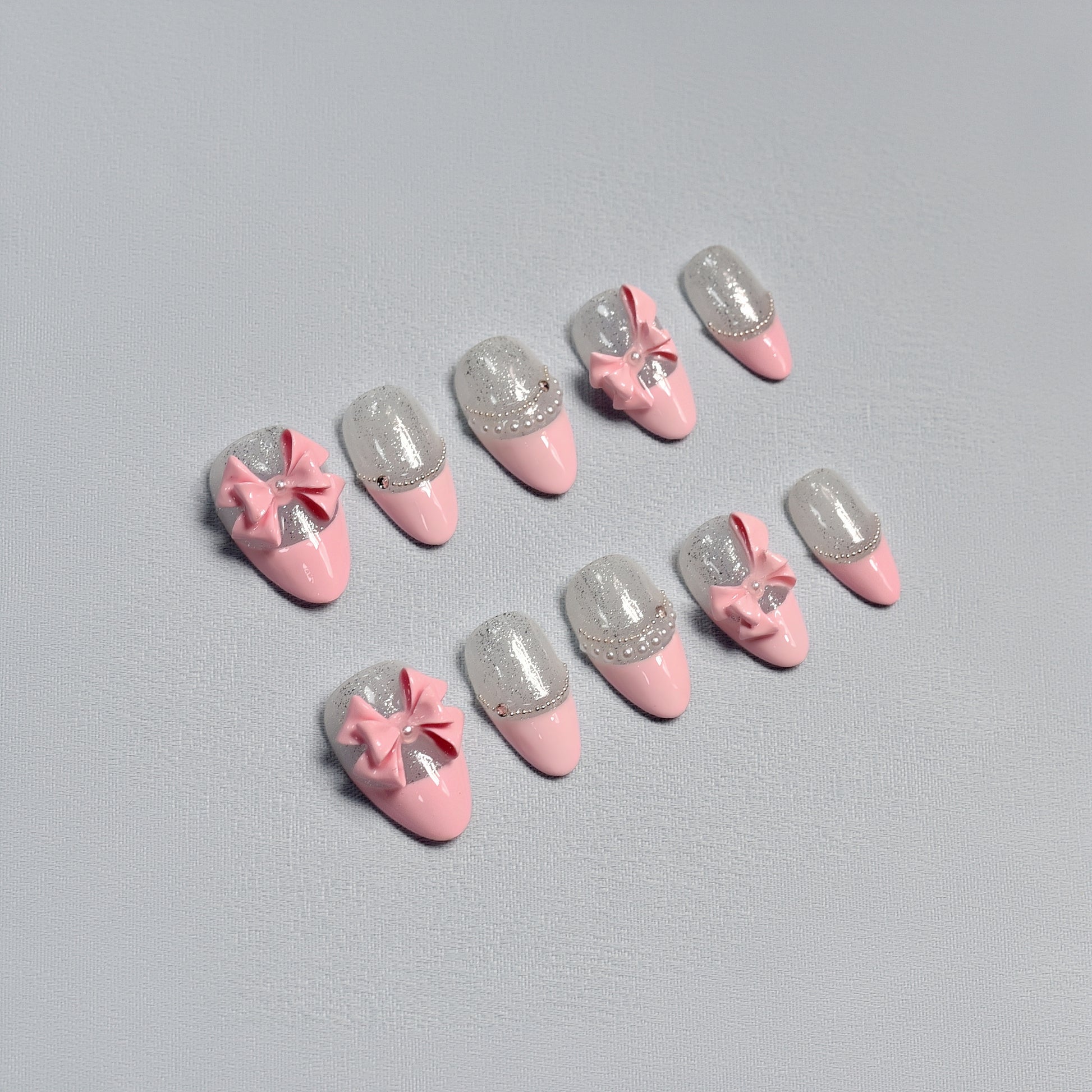 Sugar Bow handmade press-on nails by You Are Angel with pink base, silver glitter, and 3D pink bows for a soft and feminine look.