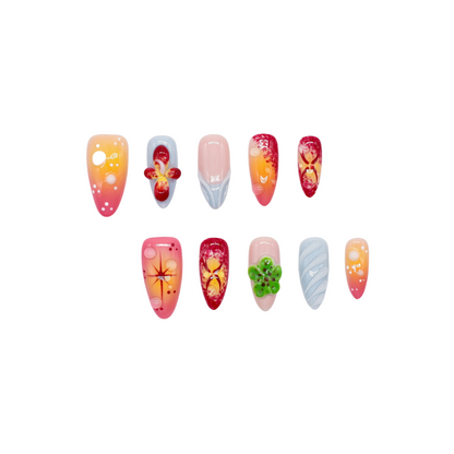 Tropical press on nails with sunset gradient, red and yellow tones, blue accents, and 3D floral charms – Tropical Bloom Collection.