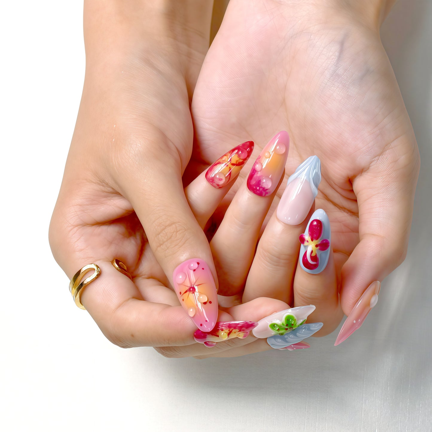 Tropical press on nails with sunset gradient, red and yellow tones, blue accents, and 3D floral charms – Tropical Bloom Collection.