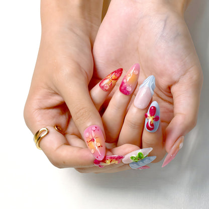 Tropical press on nails with sunset gradient, red and yellow tones, blue accents, and 3D floral charms – Tropical Bloom Collection.