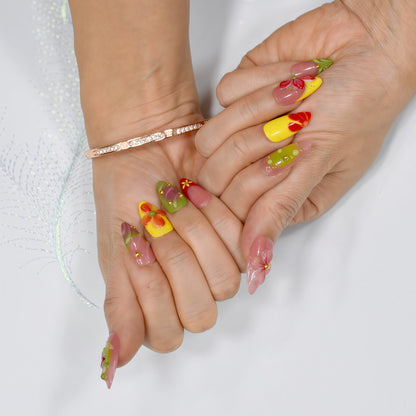 Tropical Fiesta press-on nails in long coffin shape with red, yellow, green, and lilac ombre base, 3D flowers, and gold bead accents.