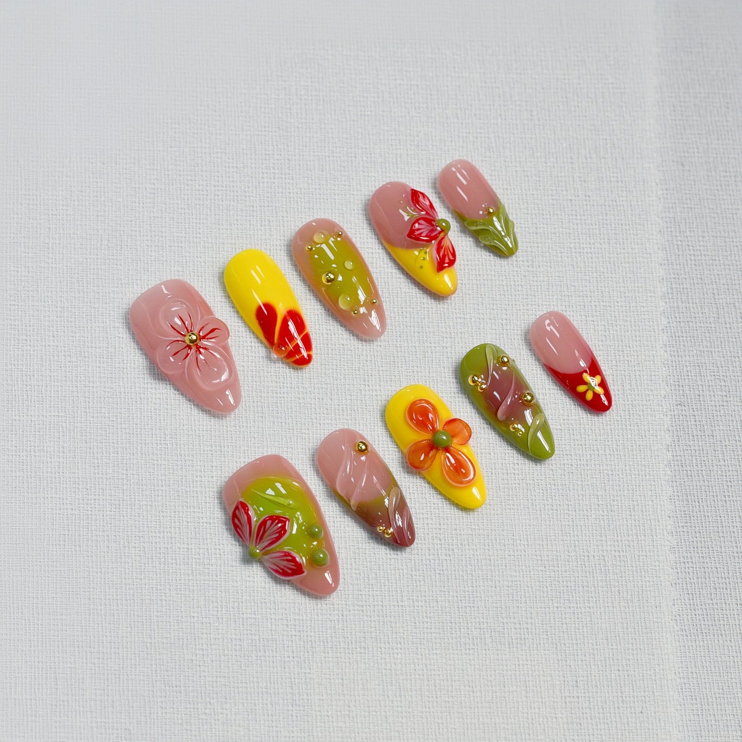 Tropical Fiesta press-on nails in long coffin shape with red, yellow, green, and lilac ombre base, 3D flowers, and gold bead accents.