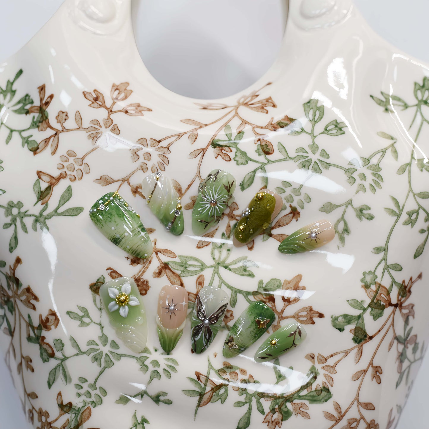 Botanical green press on nails featuring floral artwork, leaves and luxury handmade details.