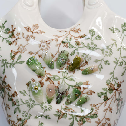 Botanical green press on nails featuring floral artwork, leaves and luxury handmade details.