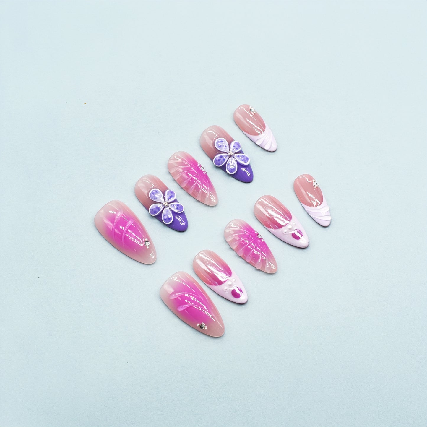 Almond-shaped press-on nails in pink-to-yellow gradient with gold beads and 3D flower accents – Sunset Bloom design.