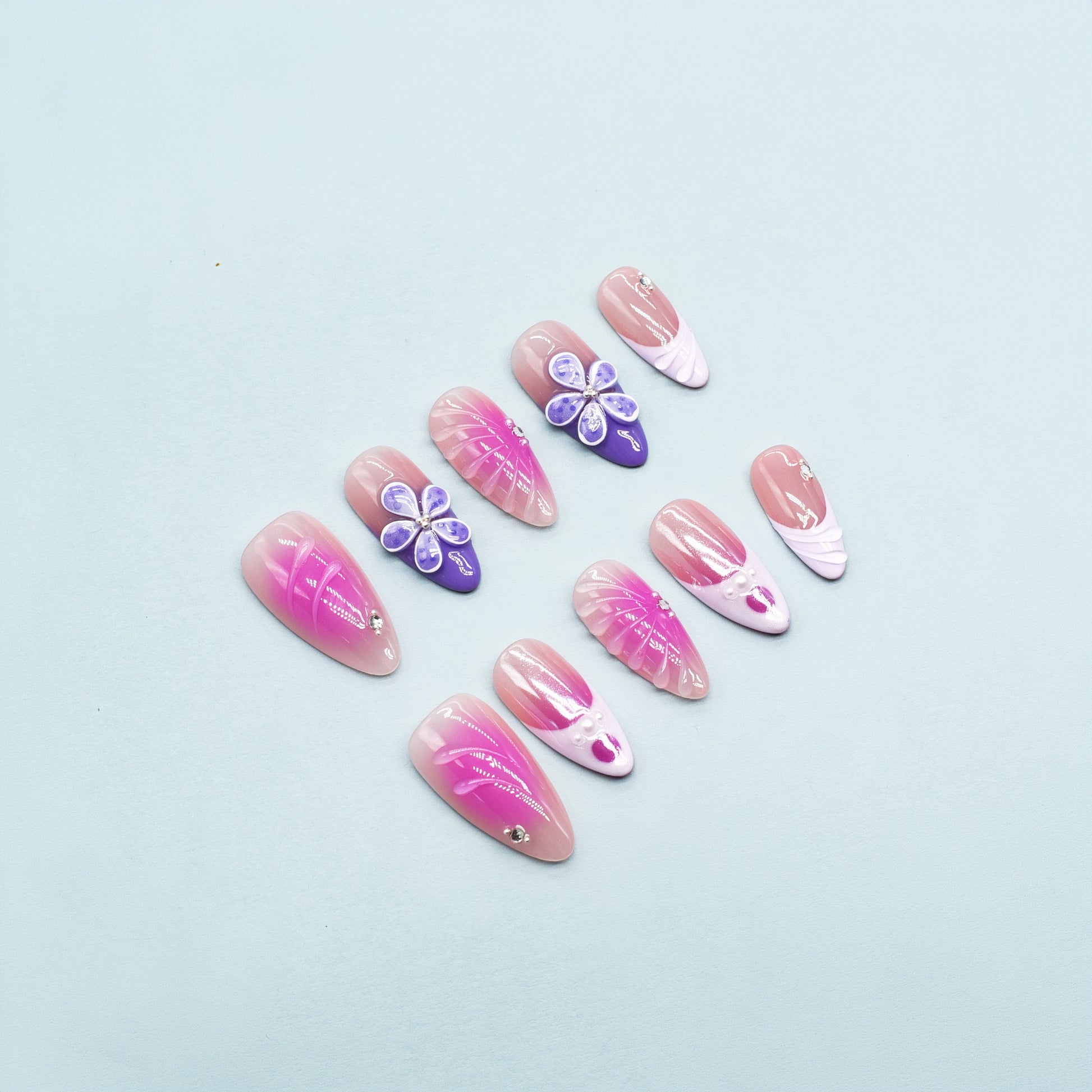 Almond-shaped press-on nails in pink-to-yellow gradient with gold beads and 3D flower accents – Sunset Bloom design.