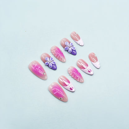 Almond-shaped press-on nails in pink-to-yellow gradient with gold beads and 3D flower accents – Sunset Bloom design.