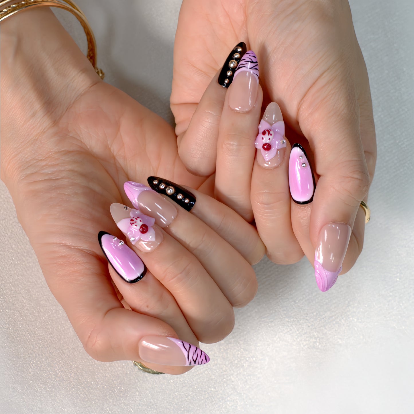 Medium Almond press-on nails in pink ombré with black zebra print, 3D orchid flowers, and rhinestone-studded accents.